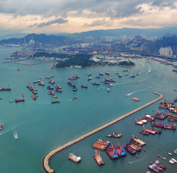 Victoria Harbor aerial view and skyline in Hong Kong with urban skyscrapers and boats.