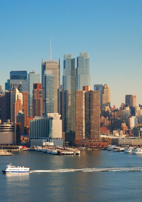 New York City skyline panorama over Hudson river with Empire State Building, boat and skyscraper.