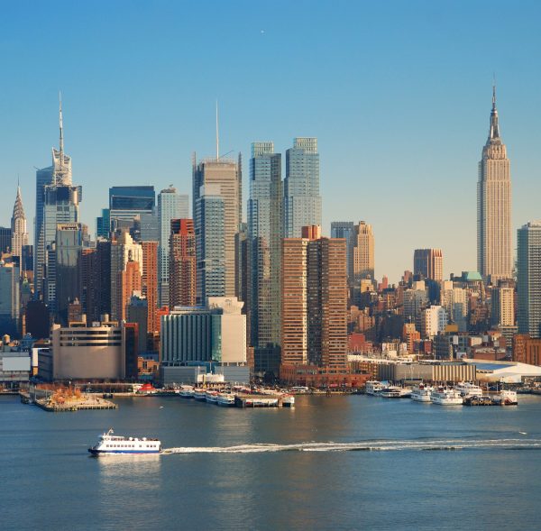 New York City skyline panorama over Hudson river with Empire State Building, boat and skyscraper.