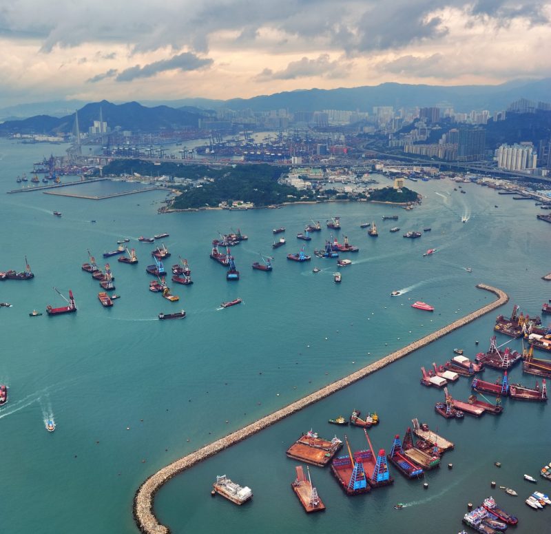 Victoria Harbor aerial view and skyline in Hong Kong with urban skyscrapers and boats.